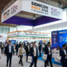 Attendees walking through the bustling exhibition hall at SEMICON India 2026, surrounded by pavilions for the India Semiconductor Mission and digital displays showcasing Semicon 2.0 initiatives.
